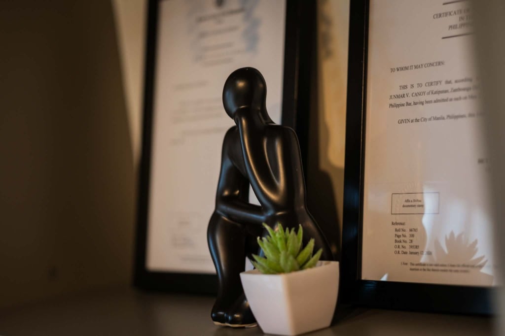 Philippine Bar certificate and decorative thinker statue in the CANOY LAW office